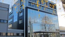 Modern office building, glass facade, black trim, 4 floors, parking lot in front