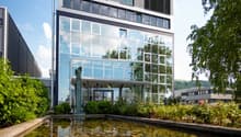 modern office building with glass facade, pond with sculpture in front