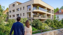 Modern apartment building, multiple floors, glass balconies, brick wall, greenery
