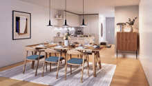 Dining room with wooden table, chairs, and a rug. There is a kitchen in the background with a coffee machine, blender, and a vase with flowers.