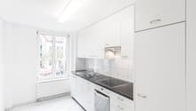 modern minimalist kitchen, white cabinets, black countertops, white tiled floor, central lighting, stainless steel sink, dishwasher, electric oven