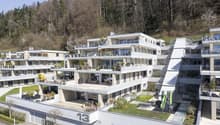 Modern multi-story building with multiple balconies, green roofs, and a playground