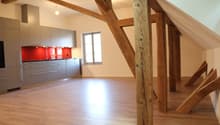 attic kitchen with wooden beams, white walls, wooden floor, modern cabinets, glass window, red tiles, silver appliances