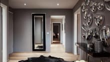 Modern room with gray walls, large mirror, wooden floor, black furry rug, console table with decorative items