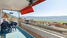 table and chairs, red and white striped awning, blue floor, metal railings, view