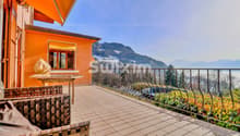 Terrasse spacieuse avec vue sur les montagnes et le lac, équipée de meubles en rotin et baignée de soleil.