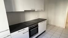 Modern kitchen with white cabinets, black countertops, white tiles, electric stove, oven, open layout, no visible washing machine or dishwasher