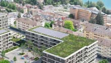 Multi-story building, solar panels on the roof, greenery, water body nearby, parking area, city skyline in the background