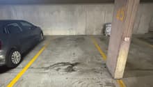 Number 45 parking space, grey car parked, yellow markings on floor, concrete walls, drainage grate