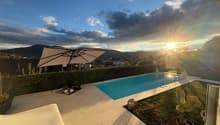Outdoor area with swimming pool, umbrella, plants, and a view of the city