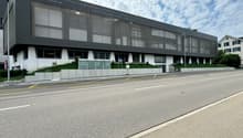 Modern office building with glass windows, concrete planters in front, road next to the building