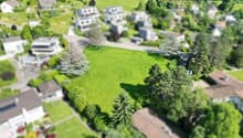 an aerial view of a building lot surrounded by houses and lush green trees and grass