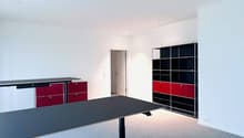 empty room, white walls, gray floor, black desk, red and black cabinets, black and red shelves
