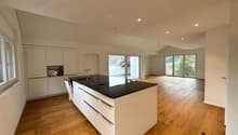 modern kitchen with island, black granite countertop, white cabinets, wooden floor, large windows, balcony