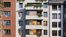 Modern apartment building with brick and concrete facade, multiple balconies, and green rooftop