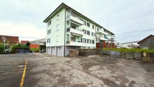 4 story building, green exterior, balconies, garage, parking lot