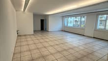large empty room, tiled floor, white walls, single entry door, long fluorescent ceiling light