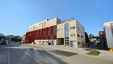 modern building, red panels, many windows, glass door, paved road