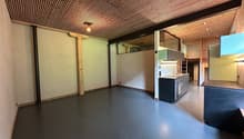 Empty kitchen with gray floor, white walls, wooden ceiling, sink, cabinets