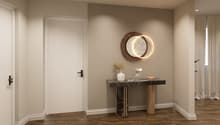 Entrance hall with wooden floor, white door, decorative table, round mirror, and decorative items