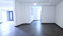 Empty room, white walls, black tiled floor, two doors, one with glass panel