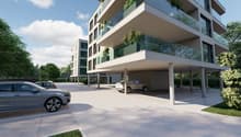 Modern apartment building with glass balconies, underground parking, and a spacious parking area.