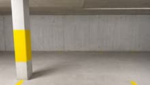 Empty parking lot with concrete walls, yellow markings, and a central column.