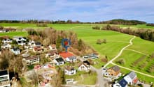 Aerial view of a neighborhood with several houses, green fields, and a winding path.