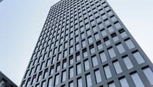 Skyscraper made of black material, many windows, modern design, urban setting
