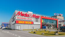 Retail complex with Media Markt, Ochsner Sport, and Maxi Bazar signage.