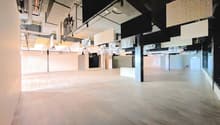Empty room, hardwood floors, black pillars, white walls, hanging art panels, recessed ceiling lights.