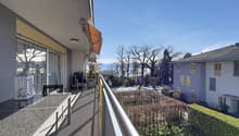 Balcony with glass railings, table, chairs, potted plant, awning, view of mountains and trees