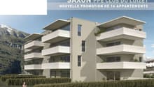 A modern apartment building with a unique design, situated in a mountainous area, featuring balconies on each floor and surrounded by greenery.