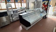 empty room with tiled floor, glass display case, microwave, refrigerator, and posters on the wall