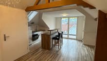 Open-concept living space with hardwood floors, wooden beams, kitchen with island, and access to a balcony or terrace.