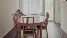 Dining room with wooden table, six chairs, wooden floor, and glass doors to a balcony