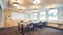 Modern empty meeting room with desks, chairs, whiteboard, and wooden paneling