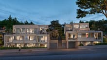 modern design, multi-story, beige walls, large windows, balconies, entrance on first floor, driveways with garages, trees in background