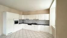 White cabinets, white countertops, black countertops, white tiled floor, built-in oven and dishwasher