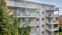 Multi-storey building, balconies, white exterior, modern design, trees in front
