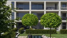 modern building with balconies, landscaped garden, wooden benches, picnic table, loungers