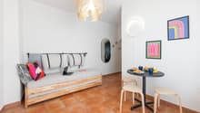 small room with a daybed, a table, and a mirror
