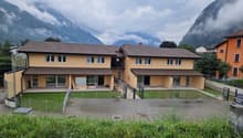 2 story house, yellow exterior, brown roof, large windows, fenced yard, mountains in the background