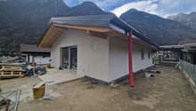 Newly constructed house, white exterior, gray roof, glass door, red chimney, construction materials around