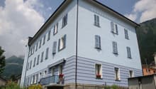 3 story white building, multiple windows, balcony, mountain view