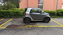 small silver car parked in parking lot in front of building