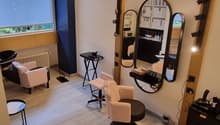 interior of a salon with a window, radiator, mirrors, two armchairs, two stools, and small tables