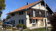 2 story house, red roof, brown wooden walls, balcony, car parked in front