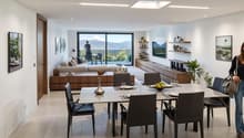 Dining room with dining table and chairs, white walls, balcony, living room with couch and coffee table, glass doors to the balcony, mountain view, pictures on the wall