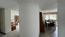 Empty room with a curved wall, a cabinet, a table, and a window.